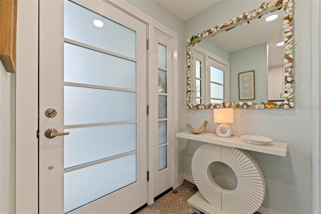 An entryway features a frosted glass door, a shell-framed mirror, and a modern console table — 479 BOCA CIEGA POINT BOULEVARD S UNIT 1205, ST PETERSBURG, FL