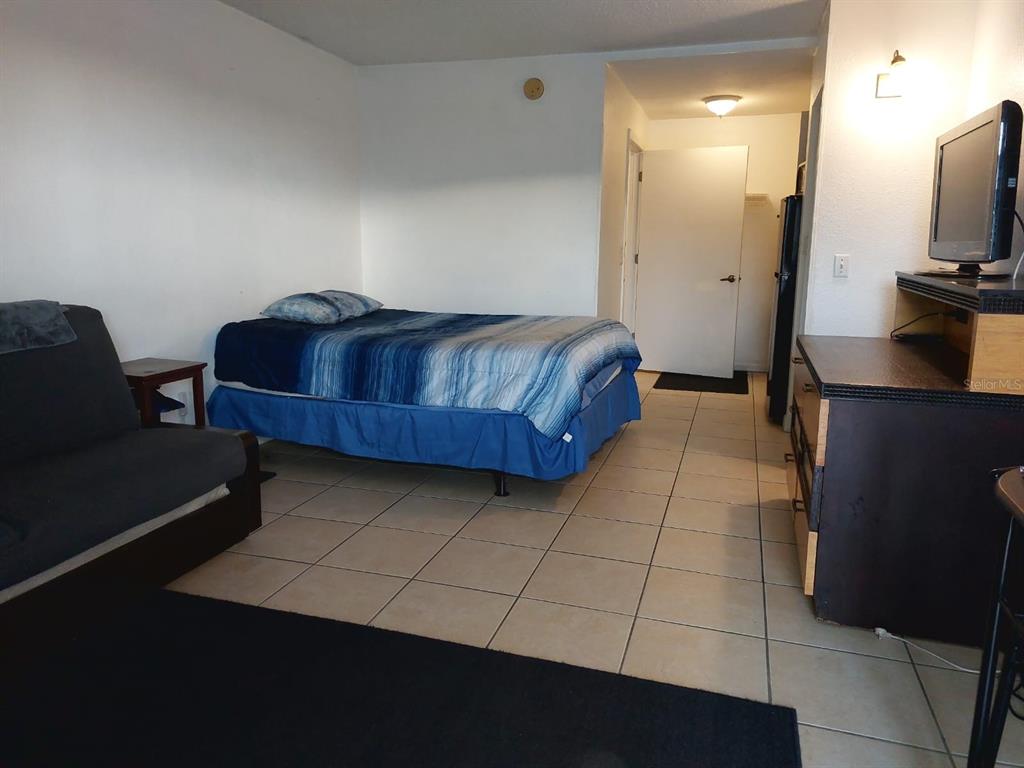 A bedroom with tile flooring, a bed with blue bedding, and a television on a dresser — 43420 HIGHWAY 27 UNIT 157, DAVENPORT, FL