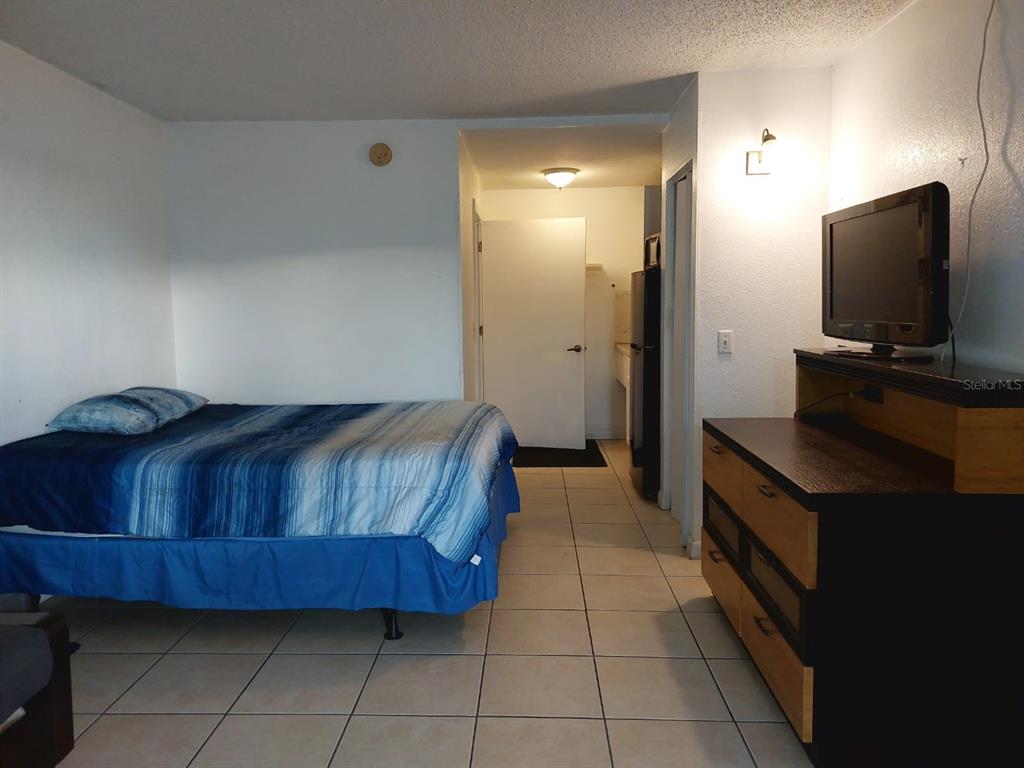 A bedroom with a bed, a dresser with a television, and a tiled floor — 43420 HIGHWAY 27 UNIT 157, DAVENPORT, FL