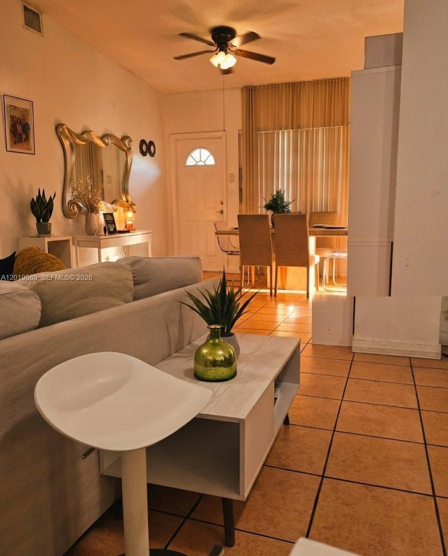 A living room with tile floors, a sofa, a coffee table, and a dining area — 571 NE 172nd St, North Miami Beach FL 33162, NORTH MIAMI BEACH, FL