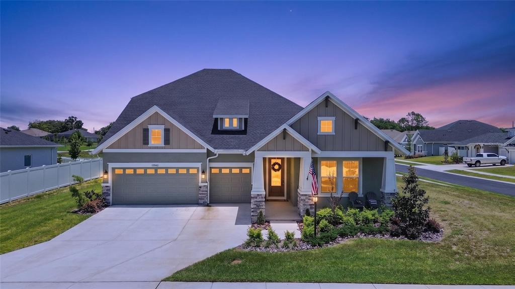 A two-story suburban house with a three-car garage, stone accents, and a front porch — 12862 CARMELA CIRCLE W, SAN ANTONIO, FL