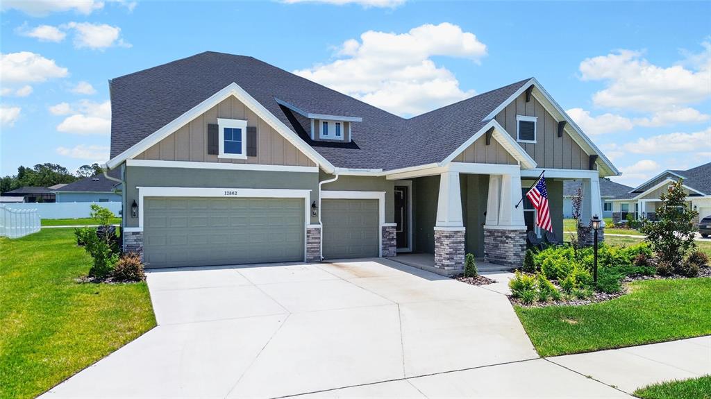 A single-story house with a two-car garage, stone accents, and a front porch — 12862 CARMELA CIRCLE W, SAN ANTONIO, FL