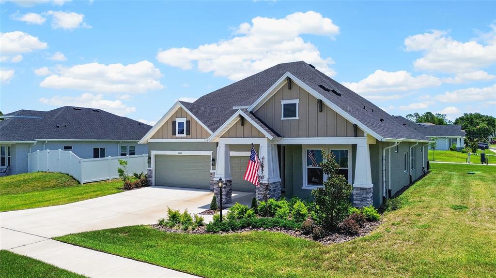 A single-story suburban house with a two-car garage, stone accents, and an American flag — 12862 CARMELA CIRCLE W, SAN ANTONIO, FL