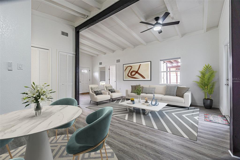 A bright living and dining area features white vaulted ceilings, gray flooring, and modern furniture — 416 COUNTRY CLUB DRIVE, OLDSMAR, FL