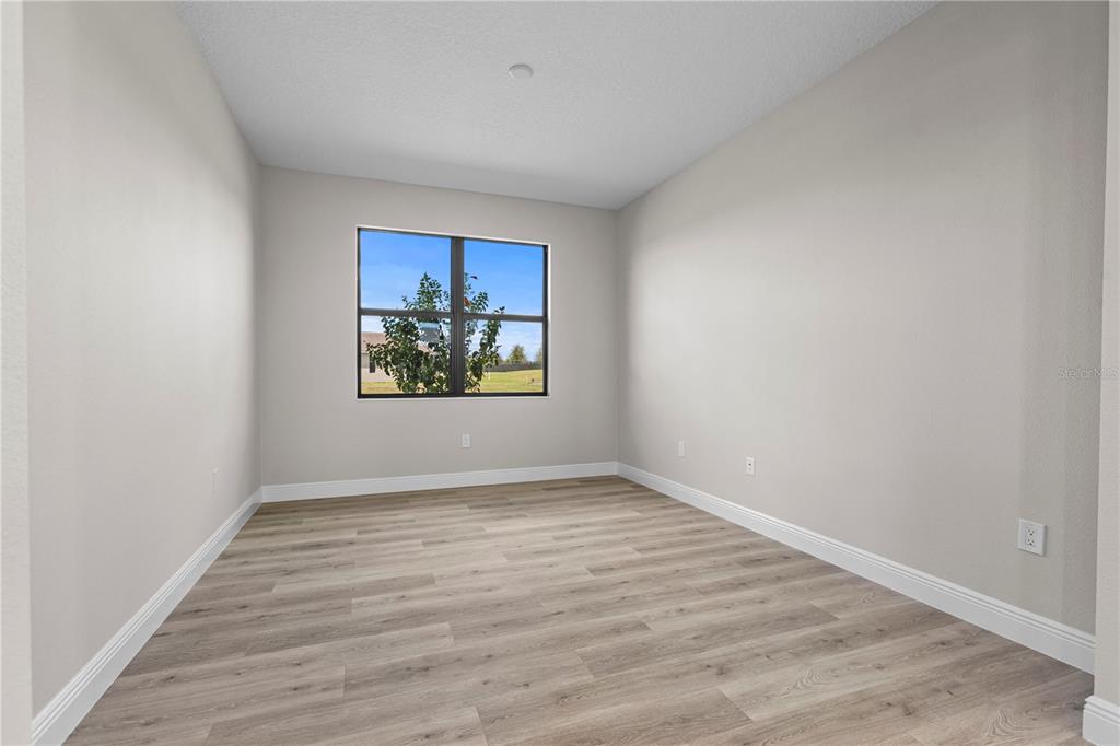 An empty room with light gray walls, wood-look flooring, and a single window — 18388 ROCKPORT PLACE, LAKEWOOD RANCH, FL