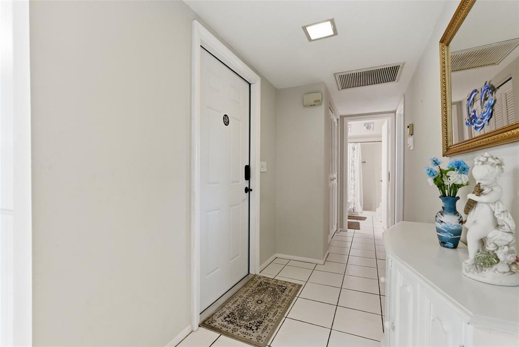 A white door opens into a tiled entryway leading to a hallway with a bathroom — 1141 MERLE WAY UNIT 14, SARASOTA, FL