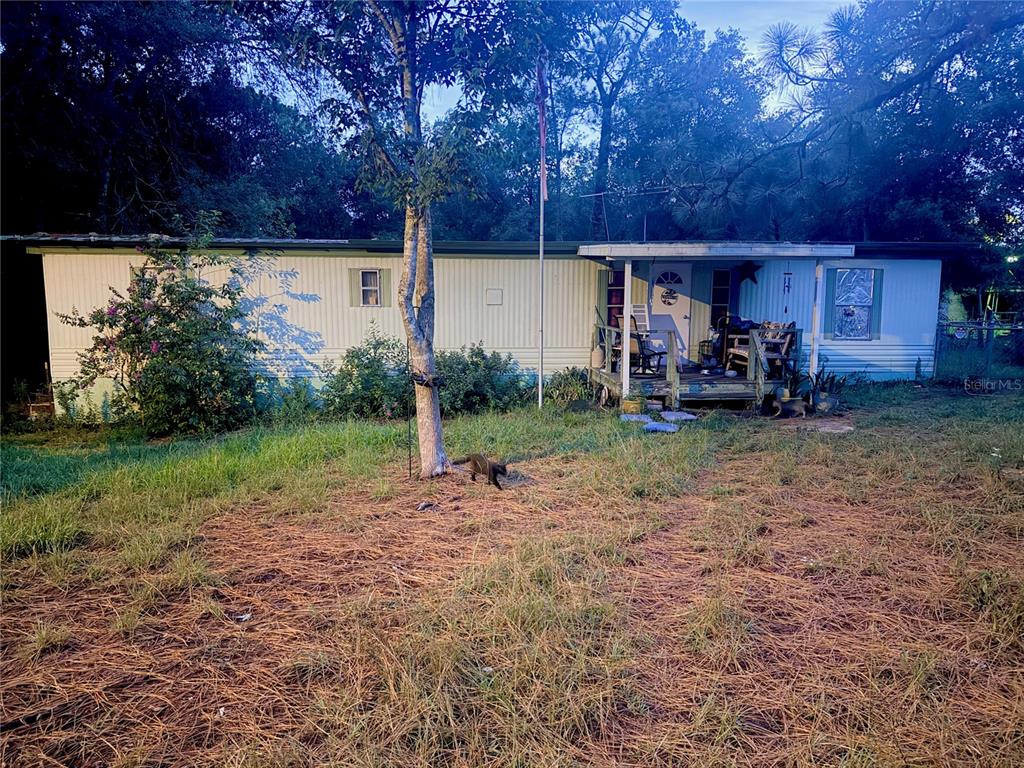 A single-story mobile home with a front porch sits on a grassy lot with trees — 6363 REED DRIVE, KEYSTONE HEIGHTS, FL