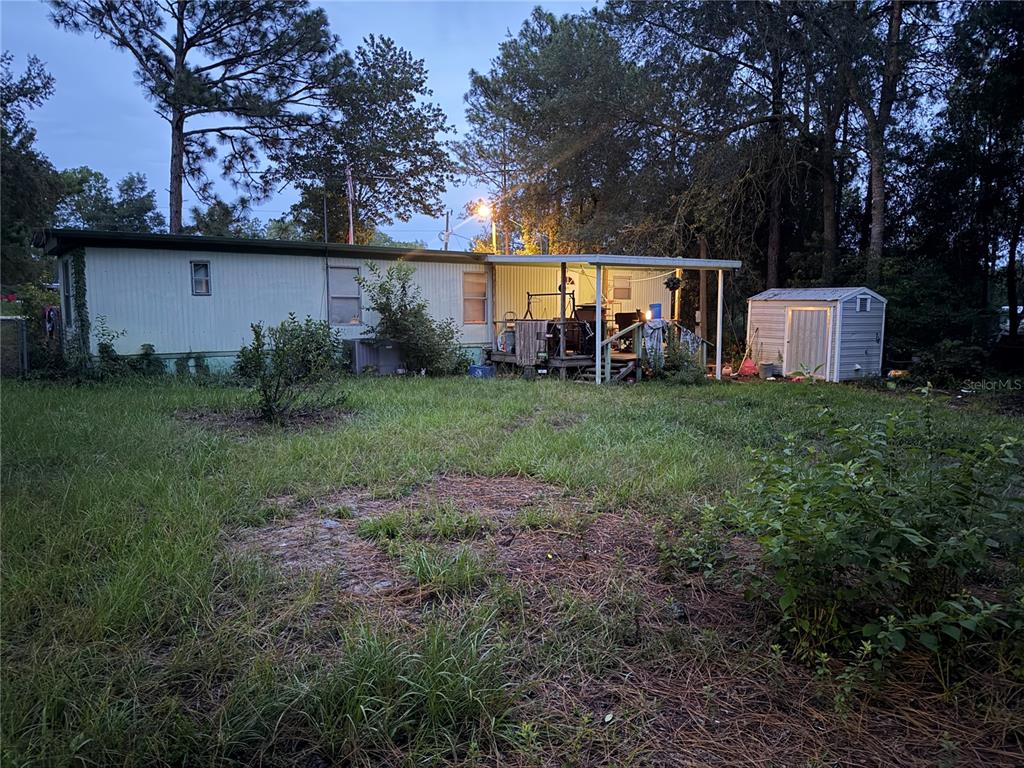 A mobile home with a covered porch and a small storage shed in the backyard — 6363 REED DRIVE, KEYSTONE HEIGHTS, FL