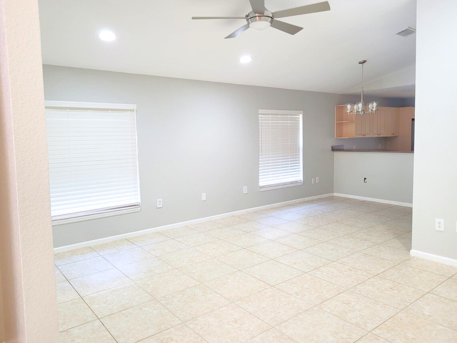 An open-concept living area features light gray walls, tile flooring, two windows, and a ceiling fan — 524 Southridge Road, Delray Beach FL 33444, DELRAY BEACH, FL