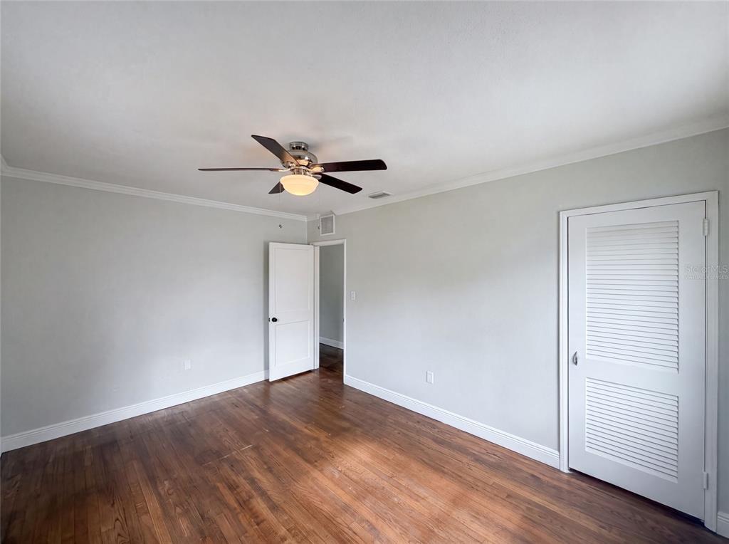An empty room features hardwood floors, light gray walls, a ceiling fan, and two doors — 6129 5TH AVENUE N, ST PETERSBURG, FL