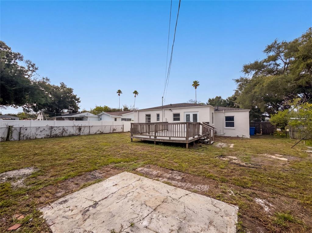 A backyard features a wooden deck attached to a white house with a concrete pad — 6129 5TH AVENUE N, ST PETERSBURG, FL