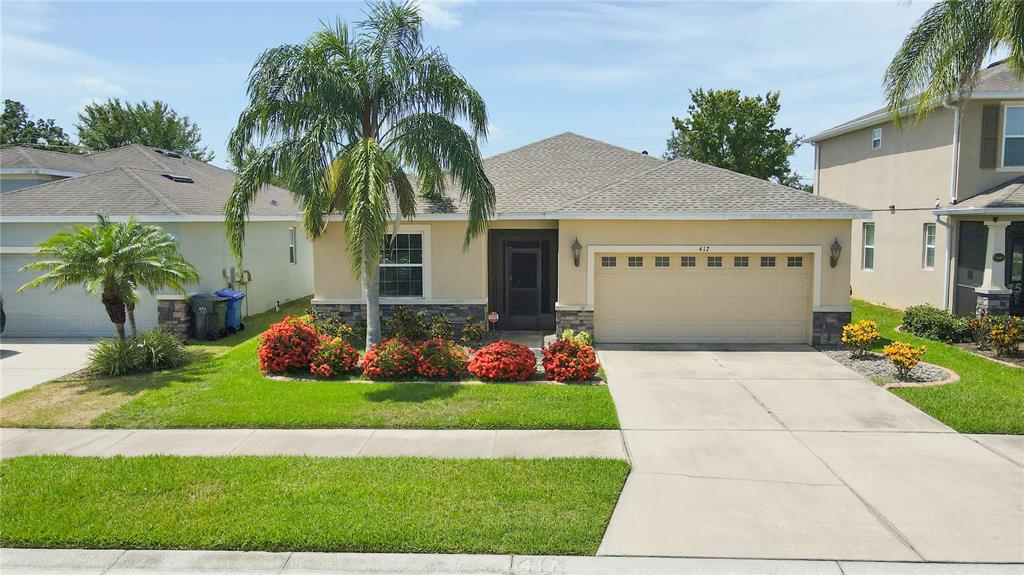 A single-story suburban house with a tan stucco exterior, a two-car garage, and landscaping — 417 BLAKELY COURT, RUSKIN, FL
