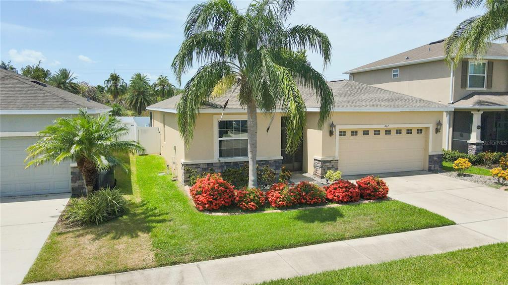A single-story house with a tan exterior, a two-car garage, and a palm tree out front — 417 BLAKELY COURT, RUSKIN, FL