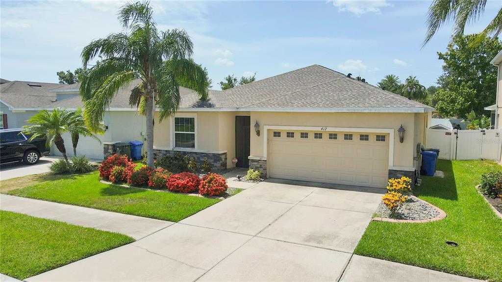A single-story house with a tan stucco exterior, a two-car garage, and a palm tree — 417 BLAKELY COURT, RUSKIN, FL
