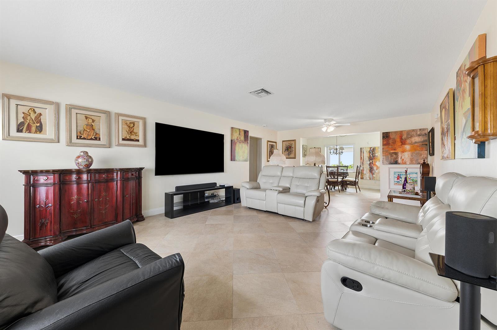 A living room features light tile floors, white leather reclining sofas, and a large television — 709 SW 15th Street, Boynton Beach FL 33426, BOYNTON BEACH, FL