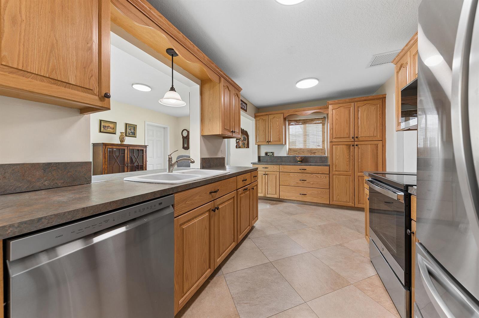 A kitchen features oak cabinets, laminate countertops, stainless steel appliances, and light-colored tile flooring — 709 SW 15th Street, Boynton Beach FL 33426, BOYNTON BEACH, FL