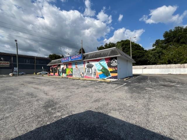 A low-slung commercial building with a mural-covered exterior sits in a large, paved parking lot — 3607 N NEBRASKA AVENUE, TAMPA, FL