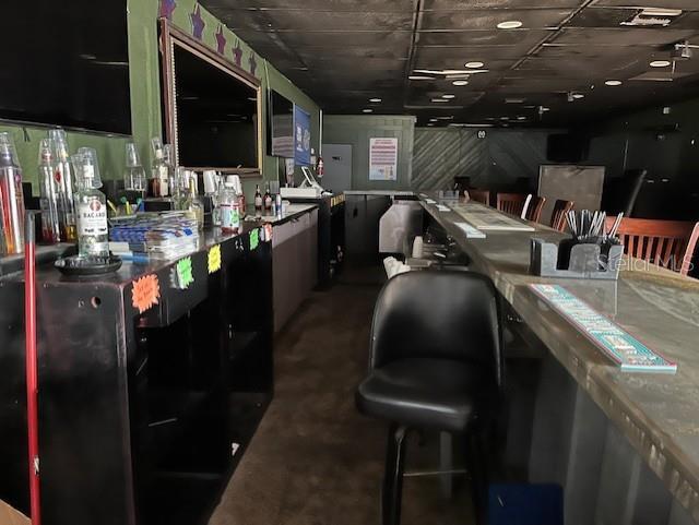 A bar interior features a long counter, a black swivel chair, and shelving with liquor bottles — 3607 N NEBRASKA AVENUE, TAMPA, FL