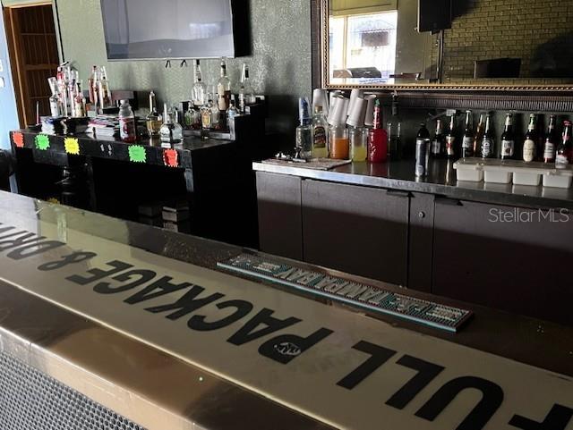 A bar area features a long counter with a drink mat and shelves stocked with bottles — 3607 N NEBRASKA AVENUE, TAMPA, FL