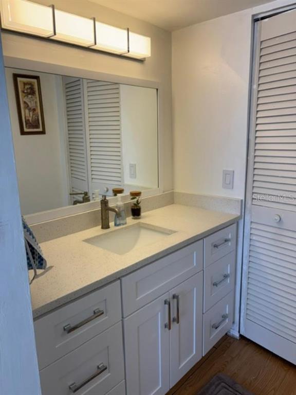 A bathroom vanity with a white cabinet, quartz countertop, and a rectangular mirror — 9700 STARKEY ROAD UNIT 113, SEMINOLE, FL