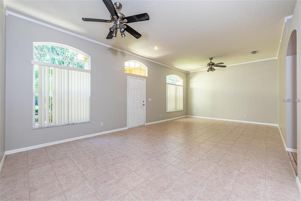 A spacious living room features light-colored tile flooring, gray walls, and two ceiling fans — 2634 BROOKVILLE DRIVE, VALRICO, FL