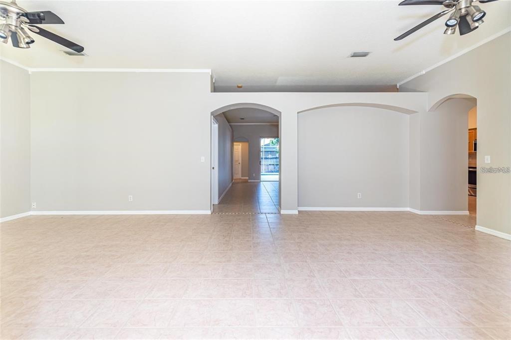 An empty living room with beige tile flooring, neutral walls, and two ceiling fans — 2634 BROOKVILLE DRIVE, VALRICO, FL