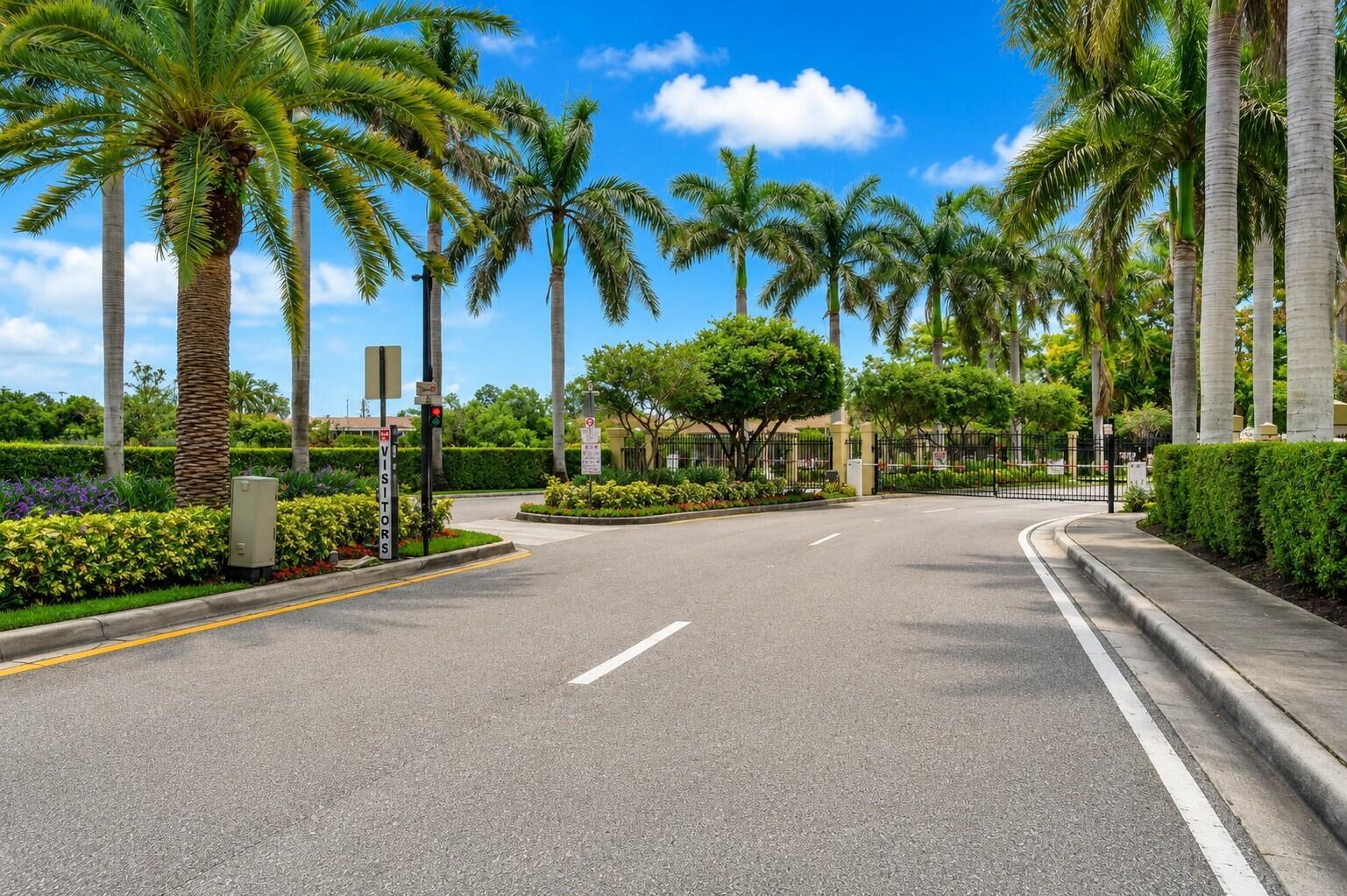 A paved road leads to a gated entrance lined with palm trees and manicured hedges — 340 Lake Monterey Circle, Boynton Beach FL 33426, BOYNTON BEACH, FL