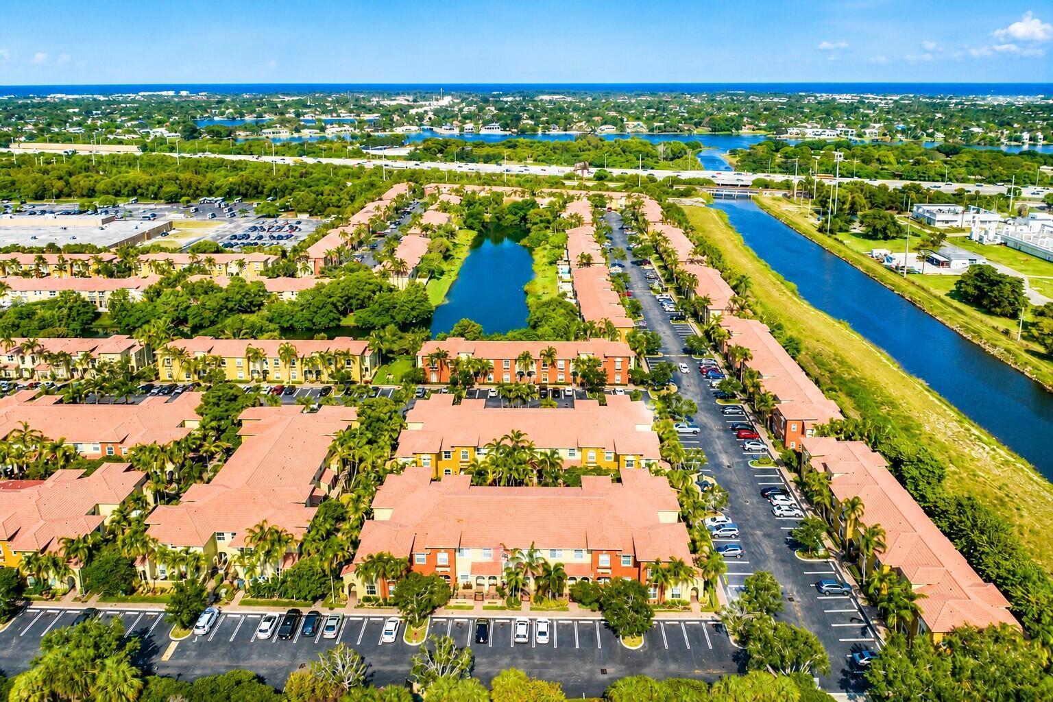 An aerial view of a multi-building residential complex with a central pond and canal — 340 Lake Monterey Circle, Boynton Beach FL 33426, BOYNTON BEACH, FL