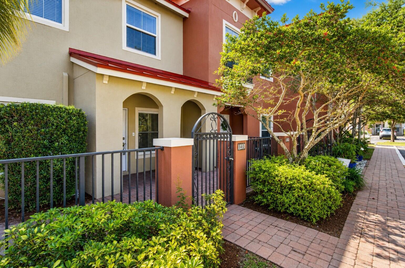 A two-story townhouse exterior features a gated courtyard, red metal roof, and brick walkway — 340 Lake Monterey Circle, Boynton Beach FL 33426, BOYNTON BEACH, FL