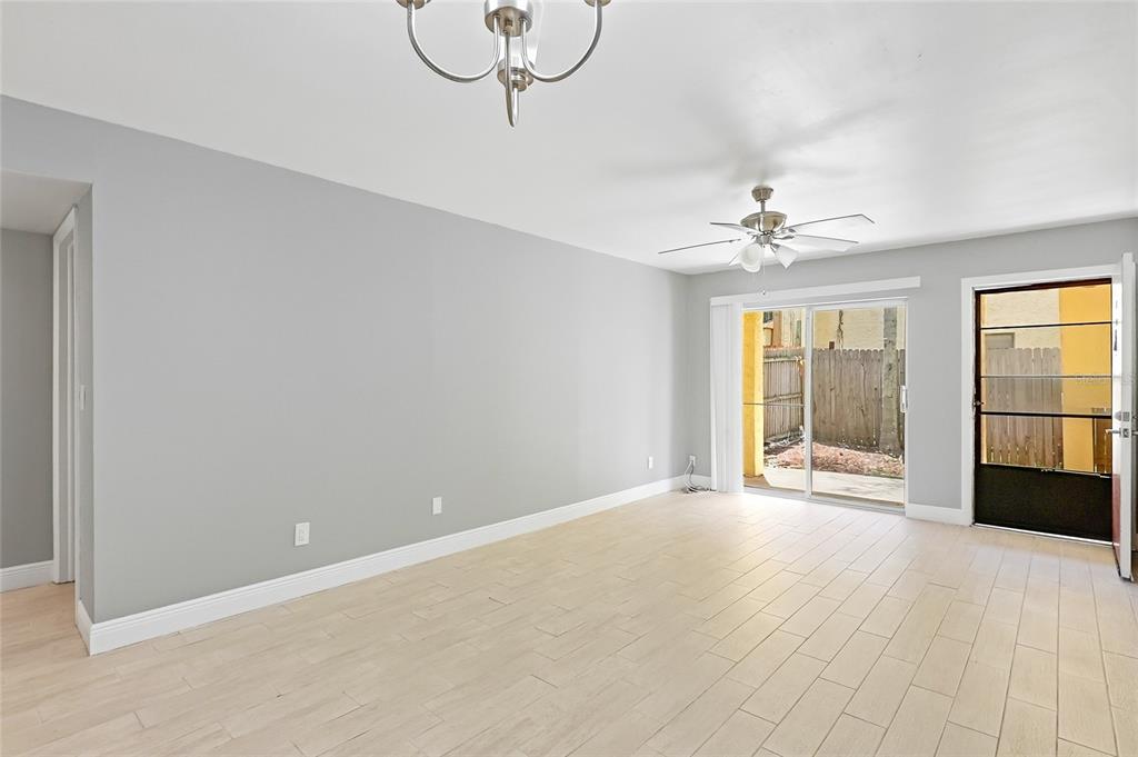 An empty room with light gray walls, light-colored tile flooring, a ceiling fan, and sliding doors — 7614 NACIDO COURT UNIT 7614, TAMPA, FL