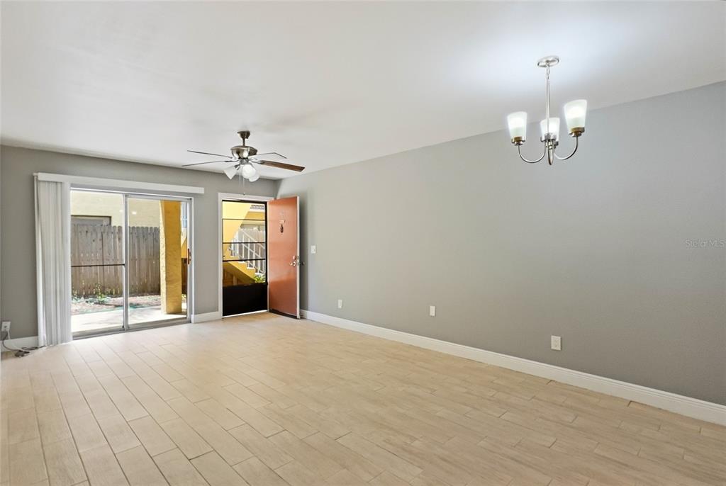 A living room with light wood-look tile flooring, a ceiling fan, and a sliding glass door — 7614 NACIDO COURT UNIT 7614, TAMPA, FL