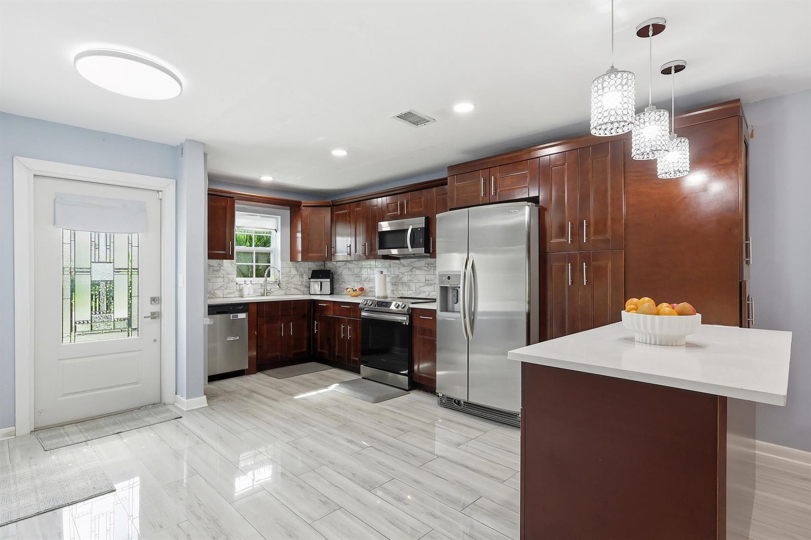 A kitchen features dark wood cabinets, stainless steel appliances, white countertops, and light tile flooring — 2520 SW 14th Court # 44, Boynton Beach FL 33426, BOYNTON BEACH, FL