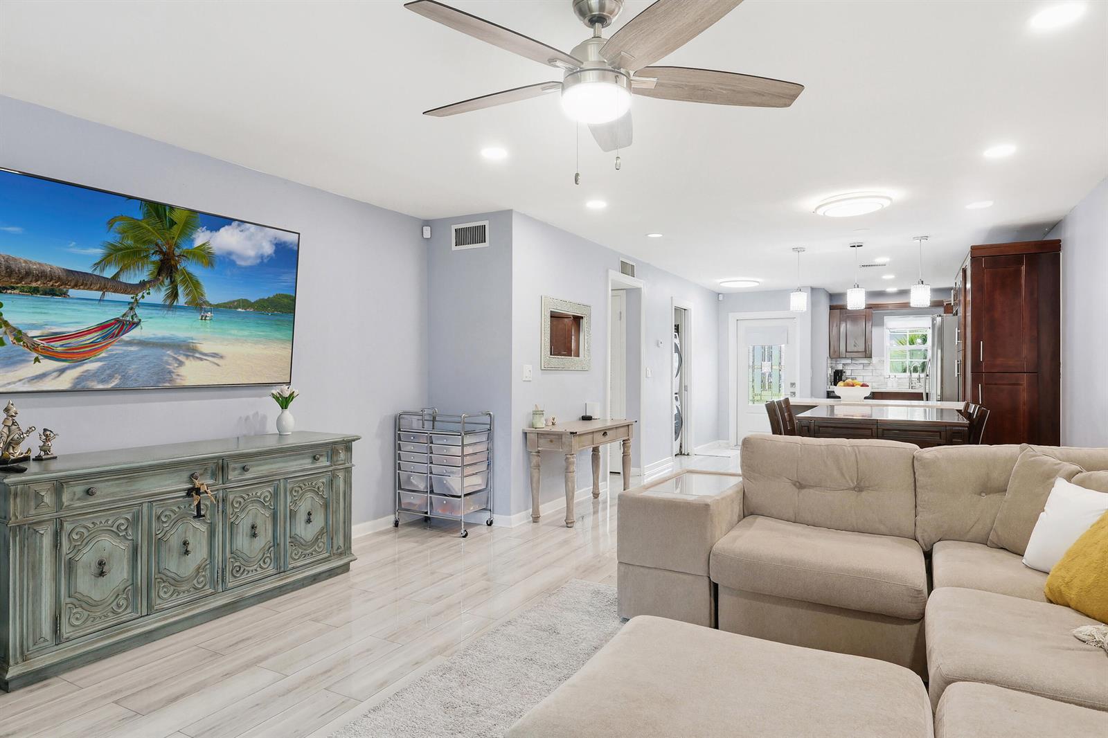 A living room with a large television, beige sectional sofa, and an open-concept kitchen — 2520 SW 14th Court # 44, Boynton Beach FL 33426, BOYNTON BEACH, FL