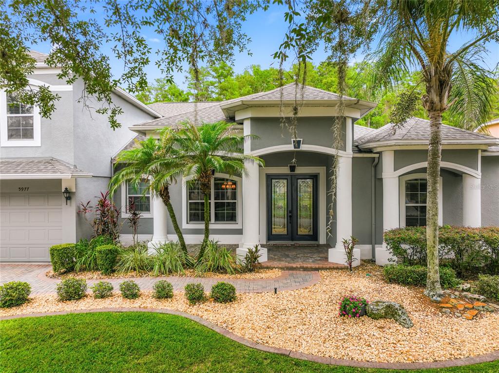 A gray single-story house features a covered entryway with white columns and a brick walkway — 5977 LAKE MELROSE DRIVE, ORLANDO, FL