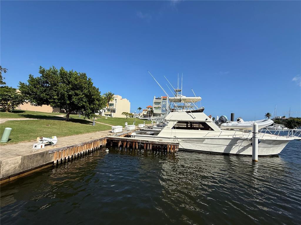 A white yacht is docked at a wooden pier next to a grassy waterfront area — A-4 PENINSULA DE SAN JUAN DRIVE, HUMACAO, PR
