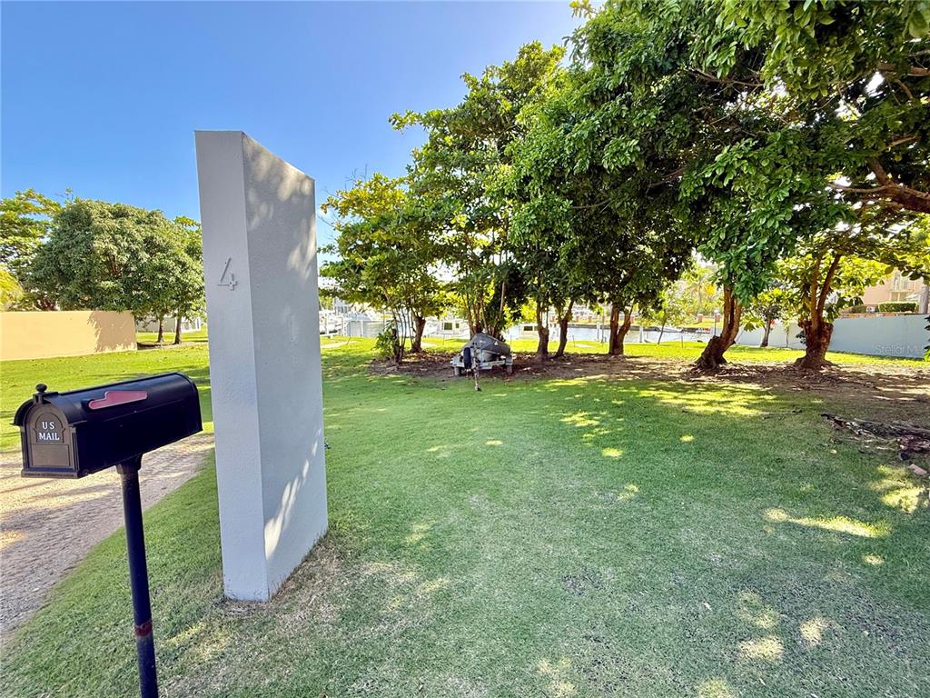 A mailbox stands next to a concrete pillar on a grassy lot with trees — A-4 PENINSULA DE SAN JUAN DRIVE, HUMACAO, PR