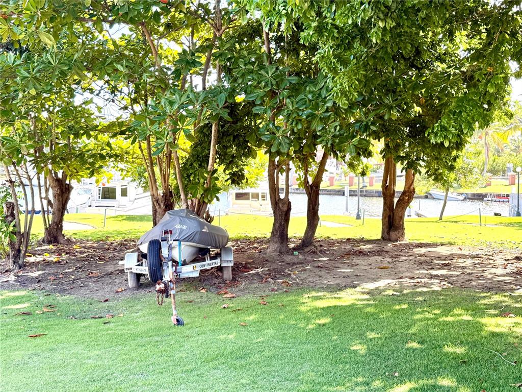 A boat on a trailer is parked under trees near a canal — A-4 PENINSULA DE SAN JUAN DRIVE, HUMACAO, PR