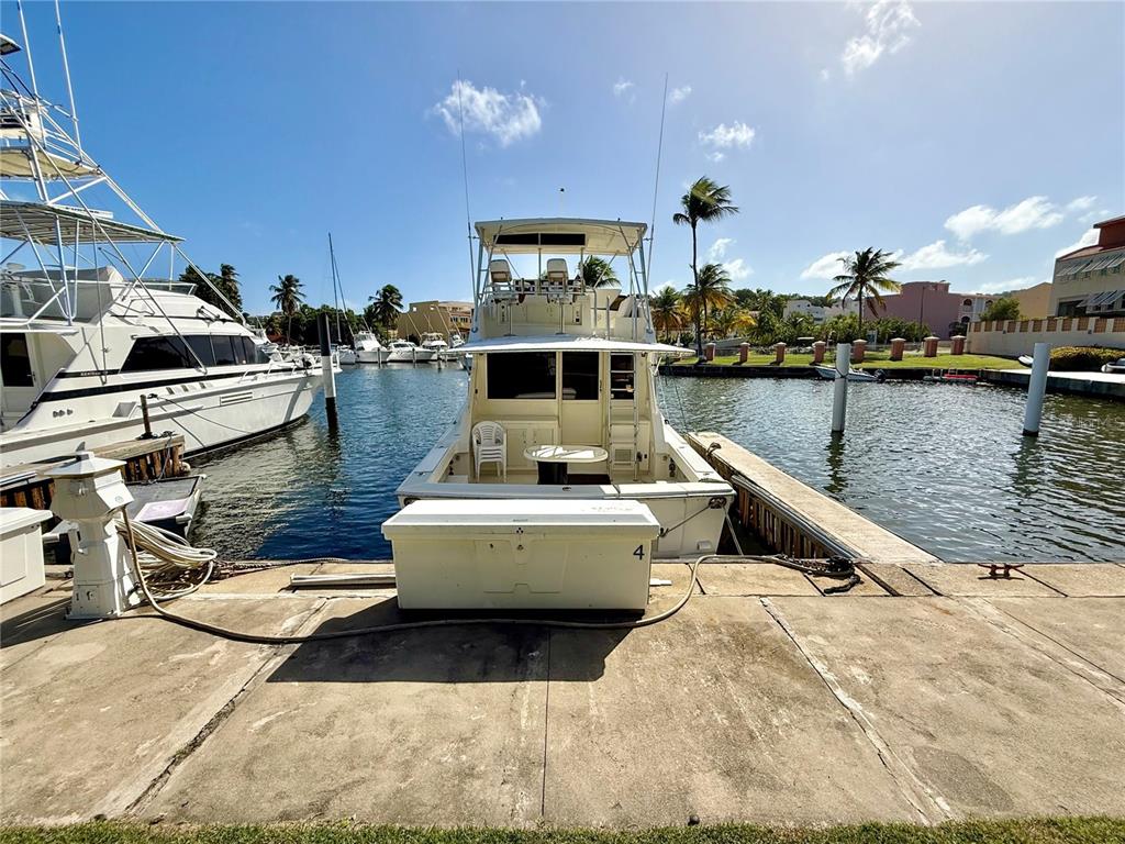 A white motor yacht is docked at a concrete pier in a sunny marina — A-4 PENINSULA DE SAN JUAN DRIVE, HUMACAO, PR
