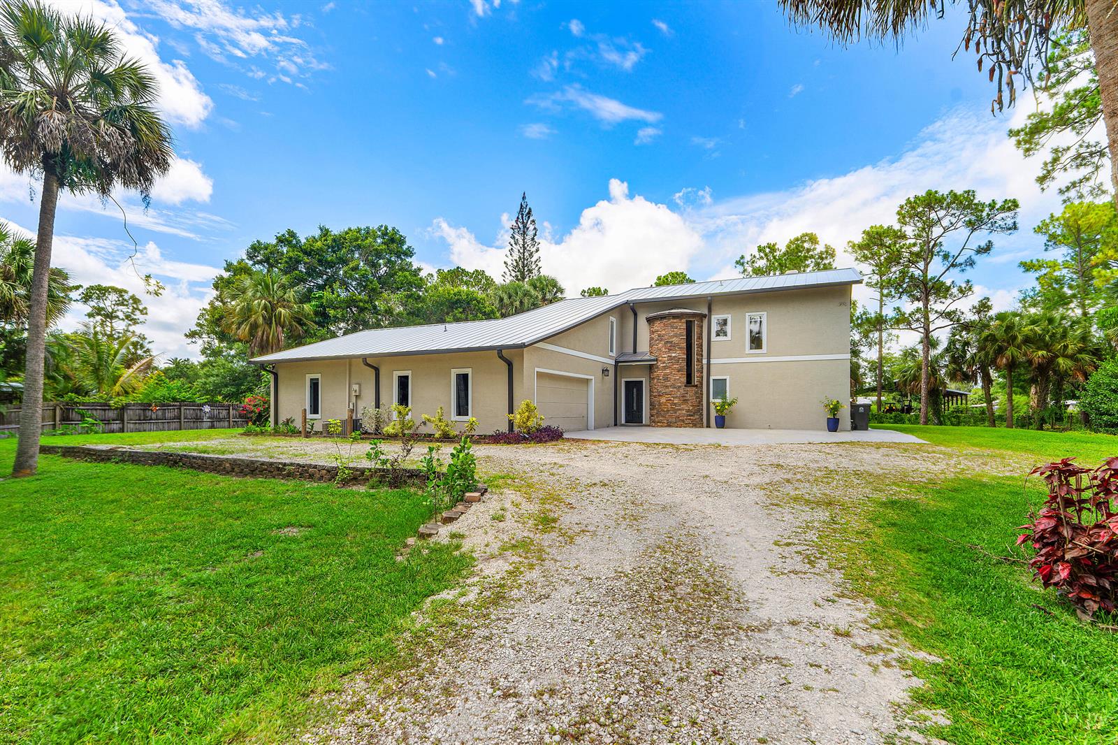 A two-story house with a stone-accented tower, metal roof, and a gravel driveway — 9743 169th Court N, Jupiter FL 33478, JUPITER, FL