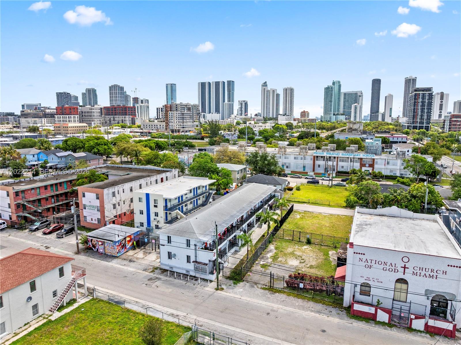 An aerial view shows a multi-story apartment building, a church, and surrounding urban development — 1829 NW 2nd Ct, Miami FL 33136, MIAMI, FL