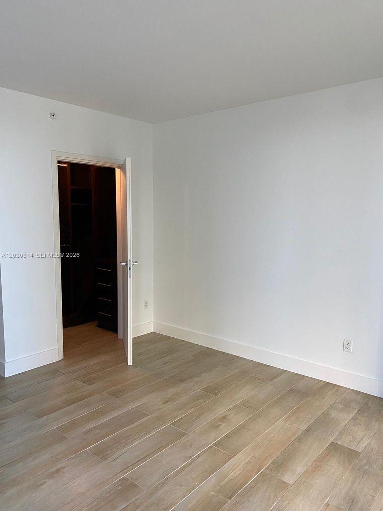 An empty room features light wood-look tile flooring, white walls, and an open closet door — 1300 Brickell Bay Dr # 1805, Miami FL 33131, MIAMI, FL