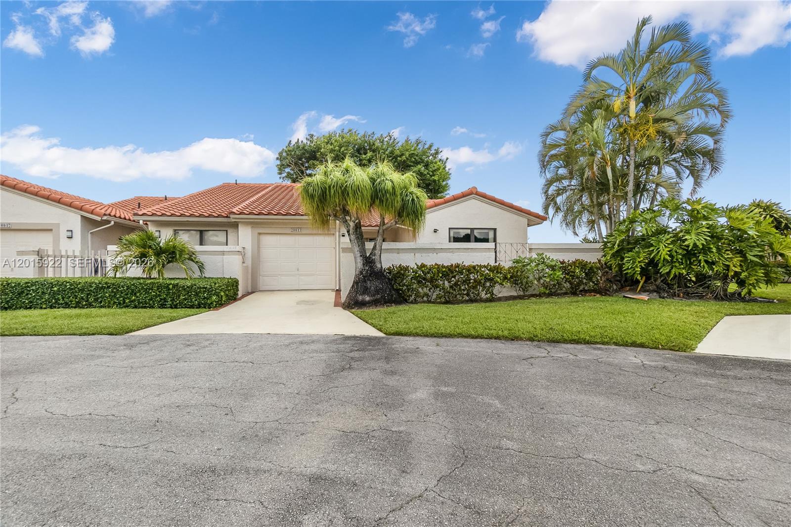 A single-story house with a tiled roof, garage, and palm trees sits behind a lawn — 20013 Mona Cir, Boca Raton FL 33434, BOCA RATON, FL