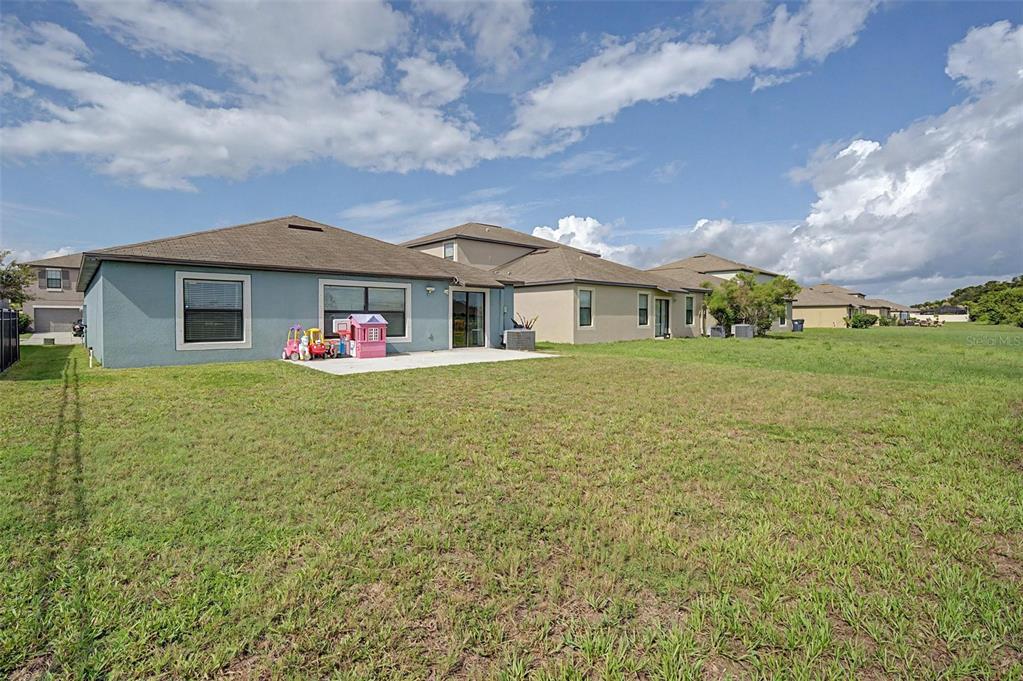 The rear exterior of a single-story house features a concrete patio and a grassy yard — 9625 SAGE CREEK DRIVE, RUSKIN, FL