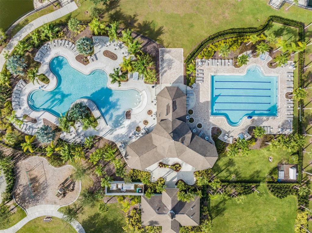 Aerial view of a community clubhouse featuring two swimming pools, a playground, and landscaped grounds — 9625 SAGE CREEK DRIVE, RUSKIN, FL