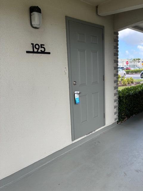 A gray exterior door labeled 195 with a hanging tag on a covered walkway — 195 Monaco E, Delray Beach FL 33446, DELRAY BEACH, FL