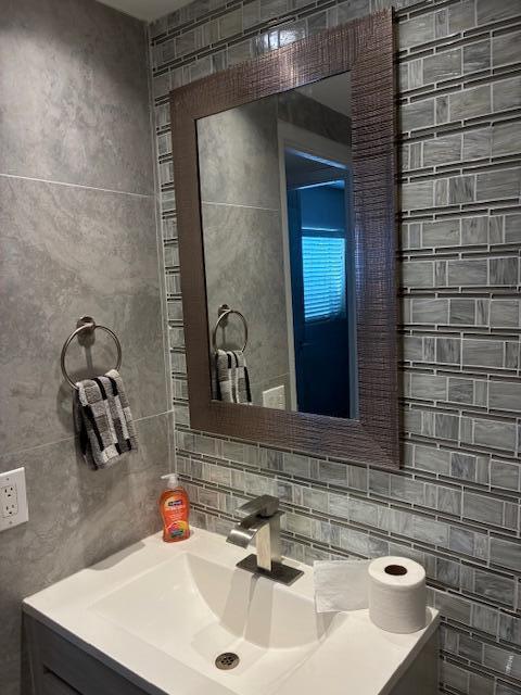 A bathroom vanity features a rectangular mirror, a modern faucet, and gray tiled walls — 195 Monaco E, Delray Beach FL 33446, DELRAY BEACH, FL