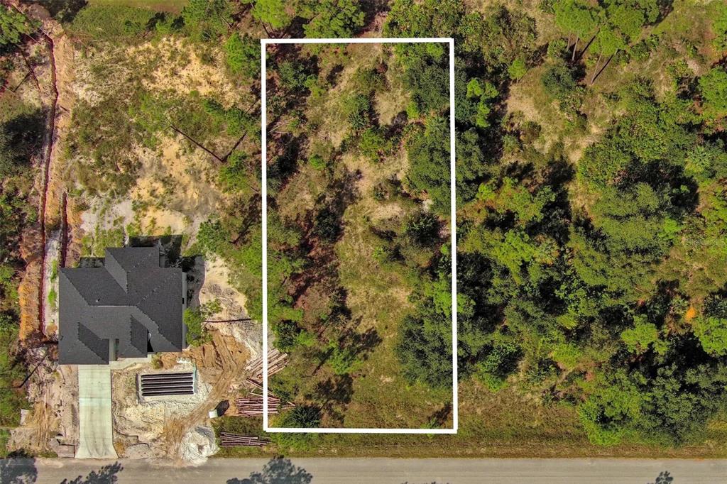 An aerial view shows a rectangular vacant lot outlined in white next to a house — 1219 WASHINGTON AVENUE, LEHIGH ACRES, FL