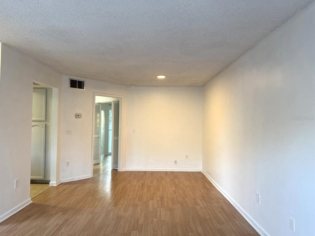 An empty room features light wood-look flooring, white walls, and a recessed ceiling light — 4308 LAKEWAY DRIVE UNIT E (50), ORLANDO, FL