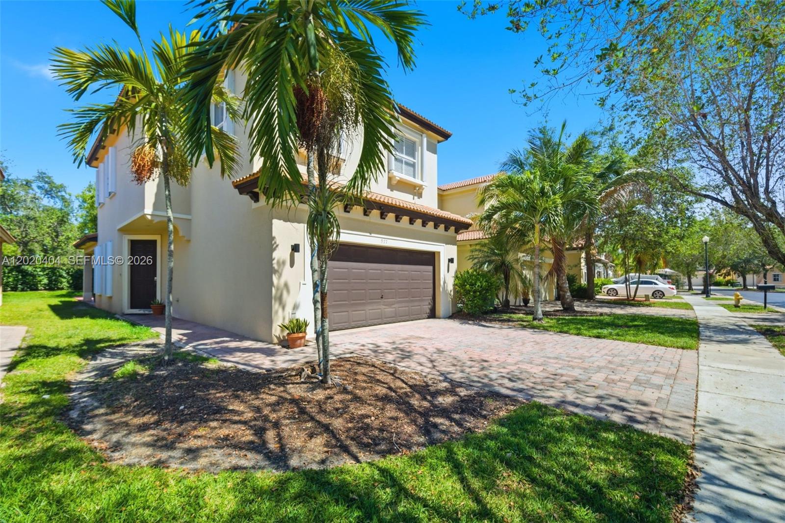 A two-story house with a brown garage door, a paved driveway, and palm trees — 977 NE 37th Pl, Homestead FL 33033, HOMESTEAD, FL