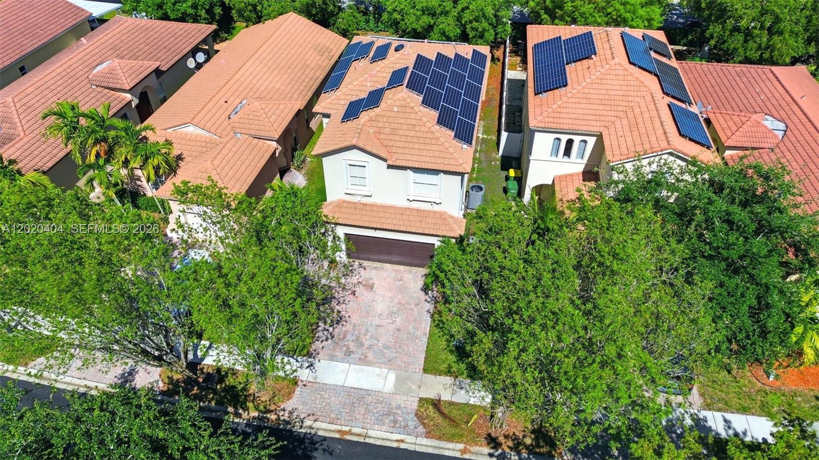 An aerial view shows two suburban houses with solar panels on their tiled roofs — 977 NE 37th Pl, Homestead FL 33033, HOMESTEAD, FL